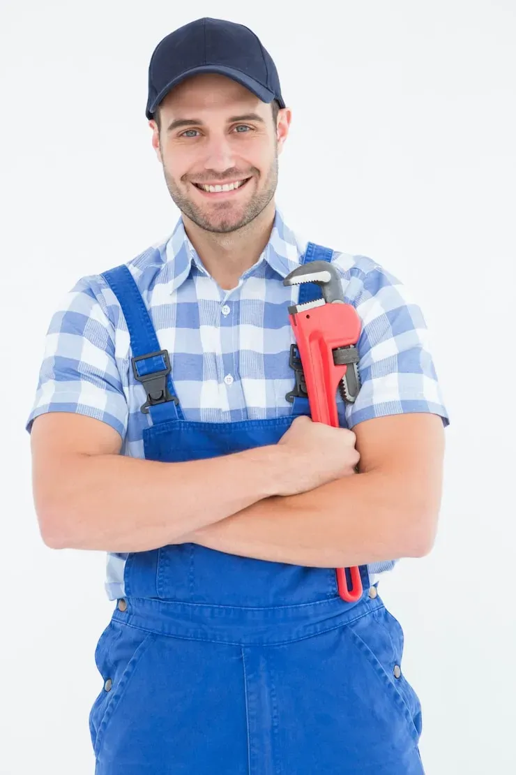 Professional plumber in blue overalls holding a red pipe wrench, providing residential plumbing services in Dallas.