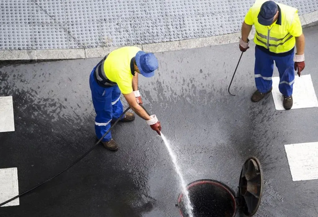 Professional Dallas plumber using high-pressure hydro-jetting equipment to clear a main sewer line.