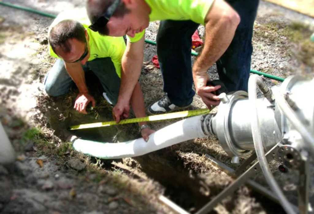 Two plumbers measuring a white lining pipe for trenchless sewer repair in Dallas.